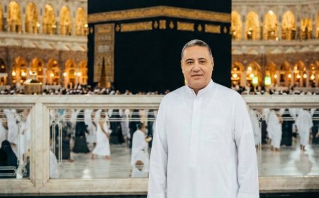 صورة واقعية لرجل يقف أمام الكعبة المشرفة ليلًا