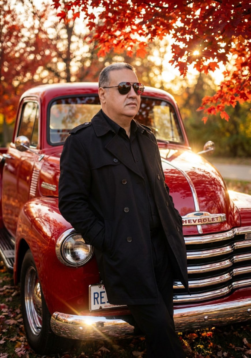 بورتريه سينمائي فائق الواقعية لرجل متكئًا على الصدام الأمامي لشاحنة شيفروليه بيك-أب كلاسيكية لامعة باللون الأحمر من خمسينيات القرن الماضي